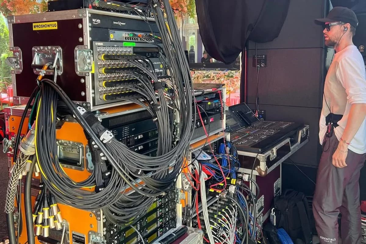 Hidden Figures — the backstage audio rack and its tangle of cables, with the sound technician at the console: the invisible architects of every show