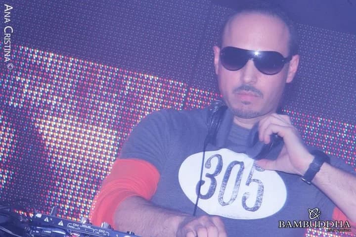 DJ Alfre en cabina con lentes de sol y camiseta con el número 305, ante una pantalla de puntos de luz, durante una presentación en el club Bambuddha de Ciudad del Este