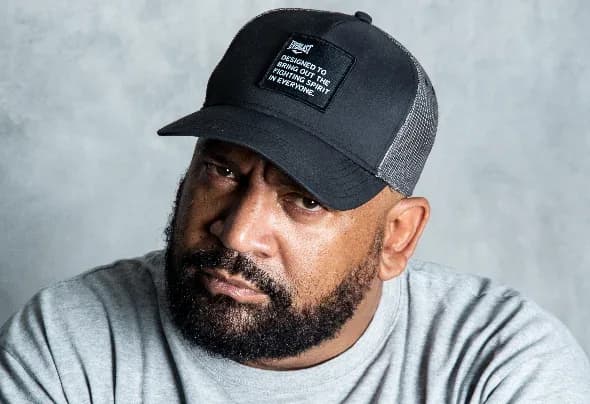 Pedro Elías Corro «DJ Babatr» en retrato actual, con barba canosa, gorra negra y camiseta gris, mirando de frente a la cámara