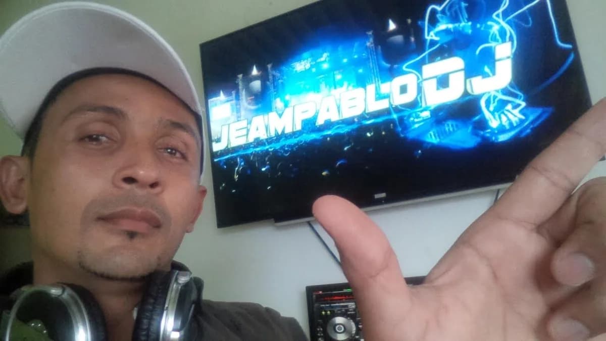 Jeampablo Mendoza con gorra blanca y audífonos al cuello, ante una pantalla con la gráfica «Jeampablo DJ»