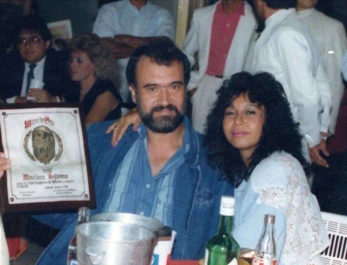 Tony Méndez, de chaqueta de jean y barba, sostiene la placa del Mara de Oro otorgada a la Miniteca Infierno —el galardón con la efigie entre laureles— acompañado en la mesa durante la celebración