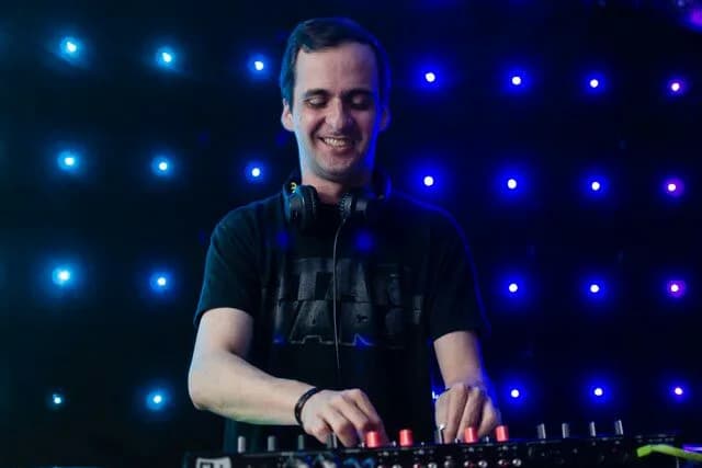 Víctor Méndez sonriente en cabina, con audífonos puestos y las manos sobre el controlador, ante un fondo de puntos de luz azules
