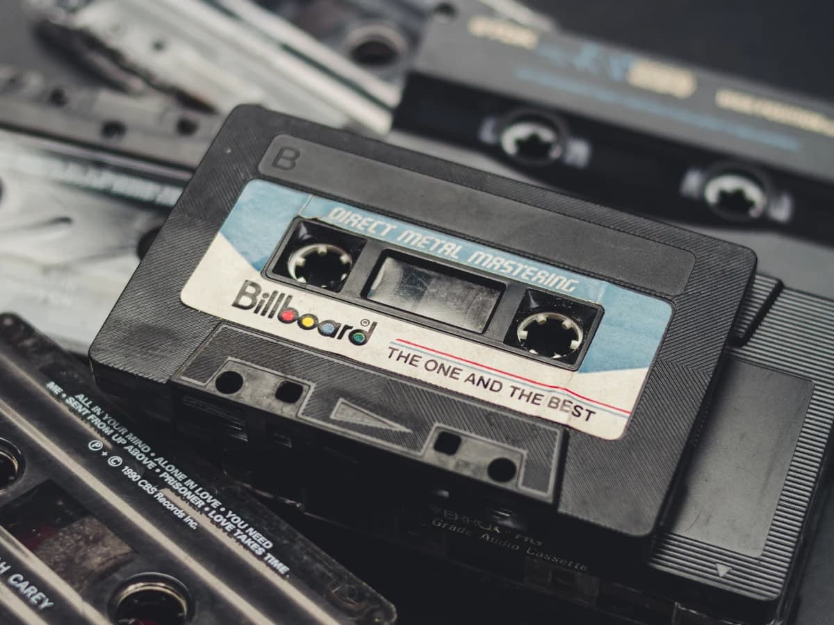 Un casete de cara B sobre un montón de cintas: la etiqueta anuncia «Direct Metal Mastering» y, en las cajas de abajo, se leen los títulos mecanografiados de una grabación casera