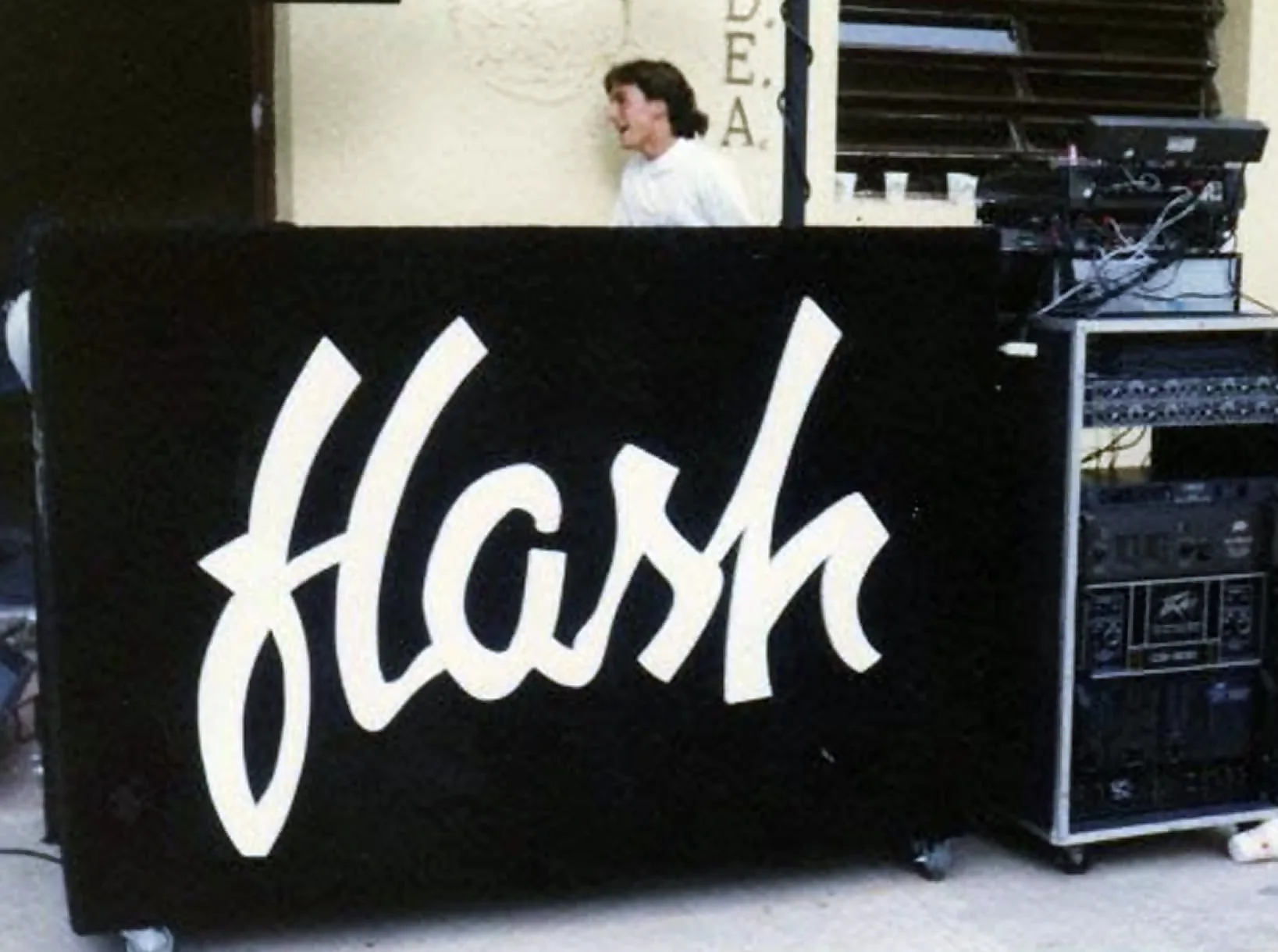 Miniteca Flash — el mueble negro rotulado «Flash» en letra cursiva blanca, junto al rack de equipos de sonido, fotografía de archivo