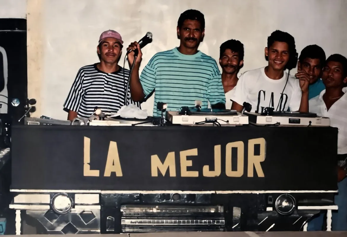 El equipo de la Miniteca Los Muertos Andantes tras su mueble rotulado «La Mejor», uno de ellos al micrófono — fotografía de los años ochenta