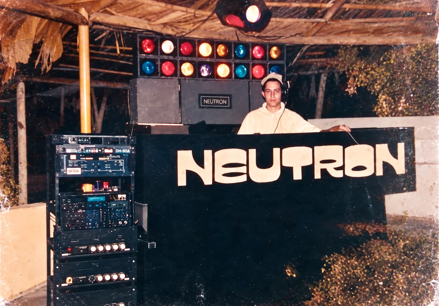 Miniteca Neutron — el discjockey Pedro Hélice Tovar en la cabina, bajo la fila de luces cocteleras y junto al mueble rotulado «Neutron», fotografía de archivo