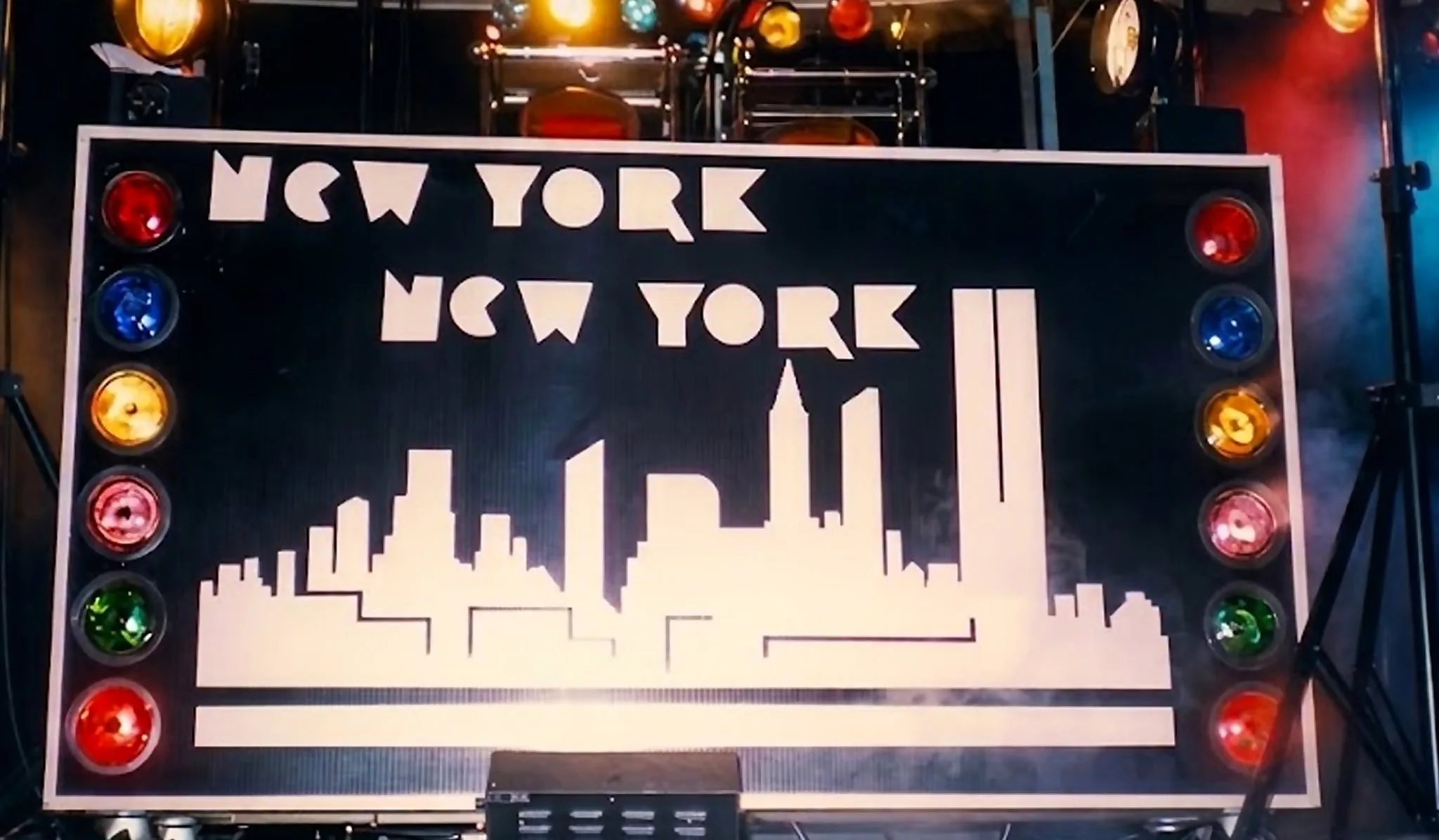 El panel «New York New York» con el perfil de Manhattan recortado, sobre la cabina, flanqueado por una bola de espejos y luces de colores