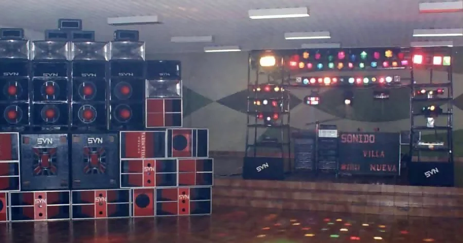 Sonido Villa Nueva — muralla de cajas de sonido de la marca SVN junto a la tarima con el letrero «Sonido Villa Nueva» y el arco de luces, fotografía de archivo