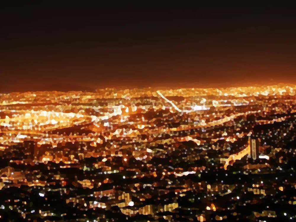 The city at night seen from above, a sea of warm lights heading toward midnight — cover art of the CMTK Radio show Buenas Noches CMTK