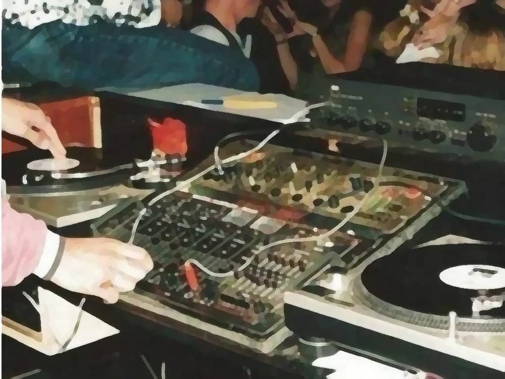 Period photograph: the hands of a discjockey on two turntables and the mixer, with the record spinning — cover art of the CMTK Radio show Clásicos en Mix Session