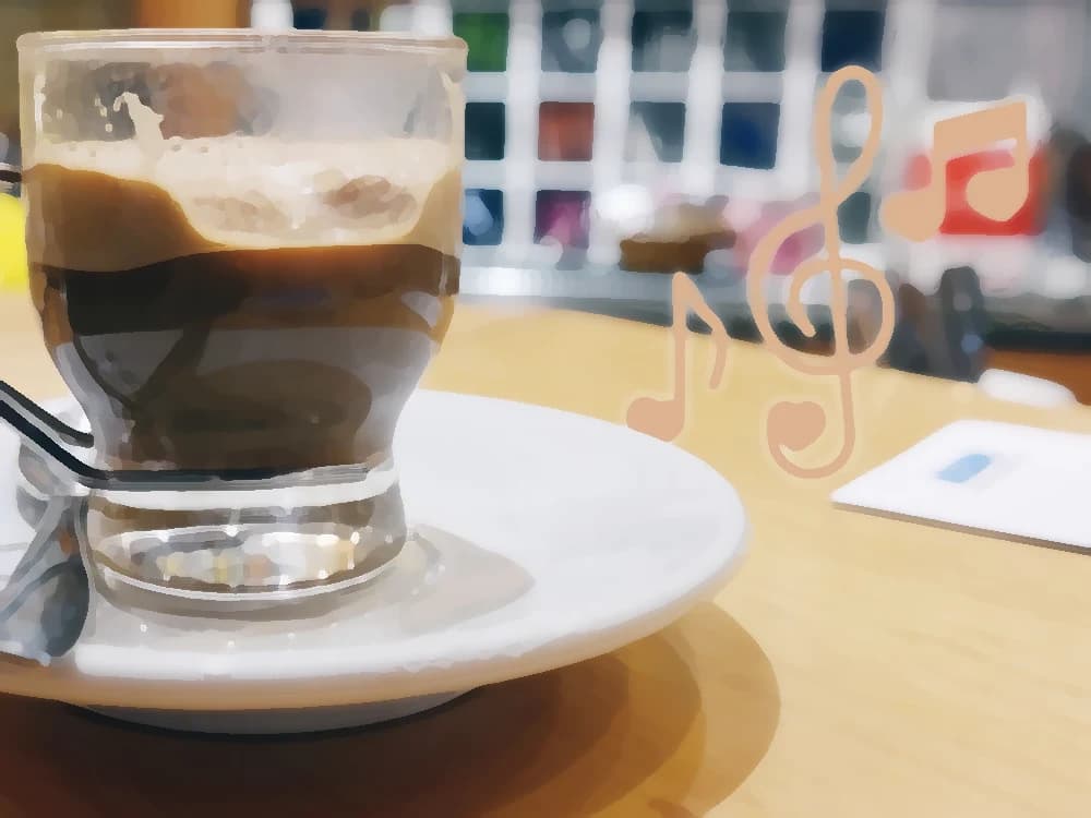 A latte served on its saucer beside a few musical notes, on the table of a midday break — cover art of the CMTK Radio show La Pausa