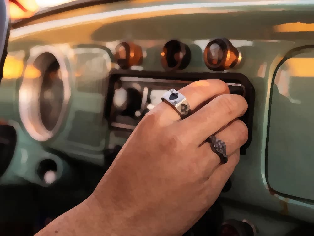 A ringed hand tunes the radio on the green dashboard of a classic car at golden hour, heading into the night — cover art of the CMTK Radio show Ruta Nocturna