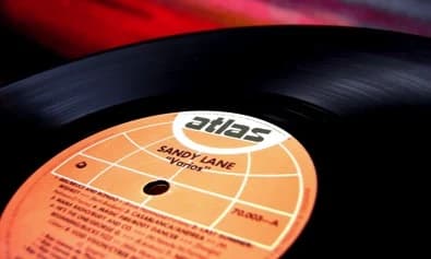 Sandy Lane (1986) — Archivo CMTK La etiqueta naranja del sello Atlas sobre el vinilo del disco de la Miniteca Sandy Lane, con el nombre impreso en el centro