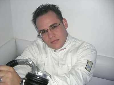 Luis Patty con lentes y chaqueta blanca, apoyado sobre unos audífonos de cabina, mirando a la cámara Luis Patty con lentes y chaqueta blanca, apoyado sobre unos audífonos de cabina, mirando a la cámara