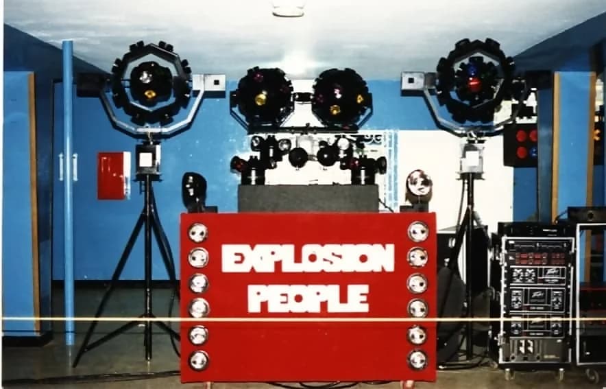 The red cabinet of the Miniteca Explosion People flanked by light heads on tripods, with the equipment rack to one side — a period photograph The red cabinet of the Miniteca Explosion People flanked by light heads on tripods, with the equipment rack to one side — a period photograph
